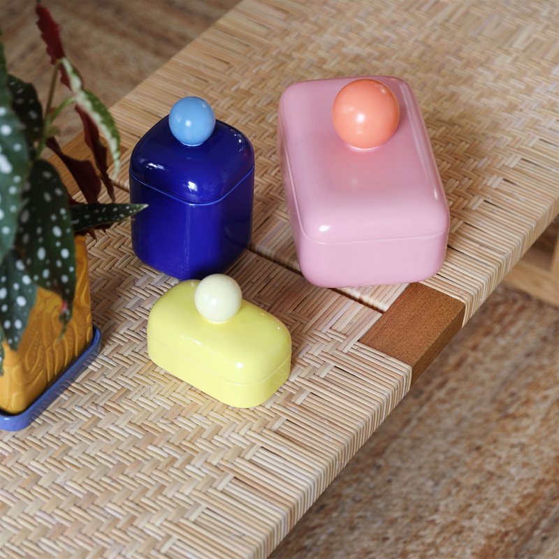 a collection of storage jars in bright colours and spherical handles on top