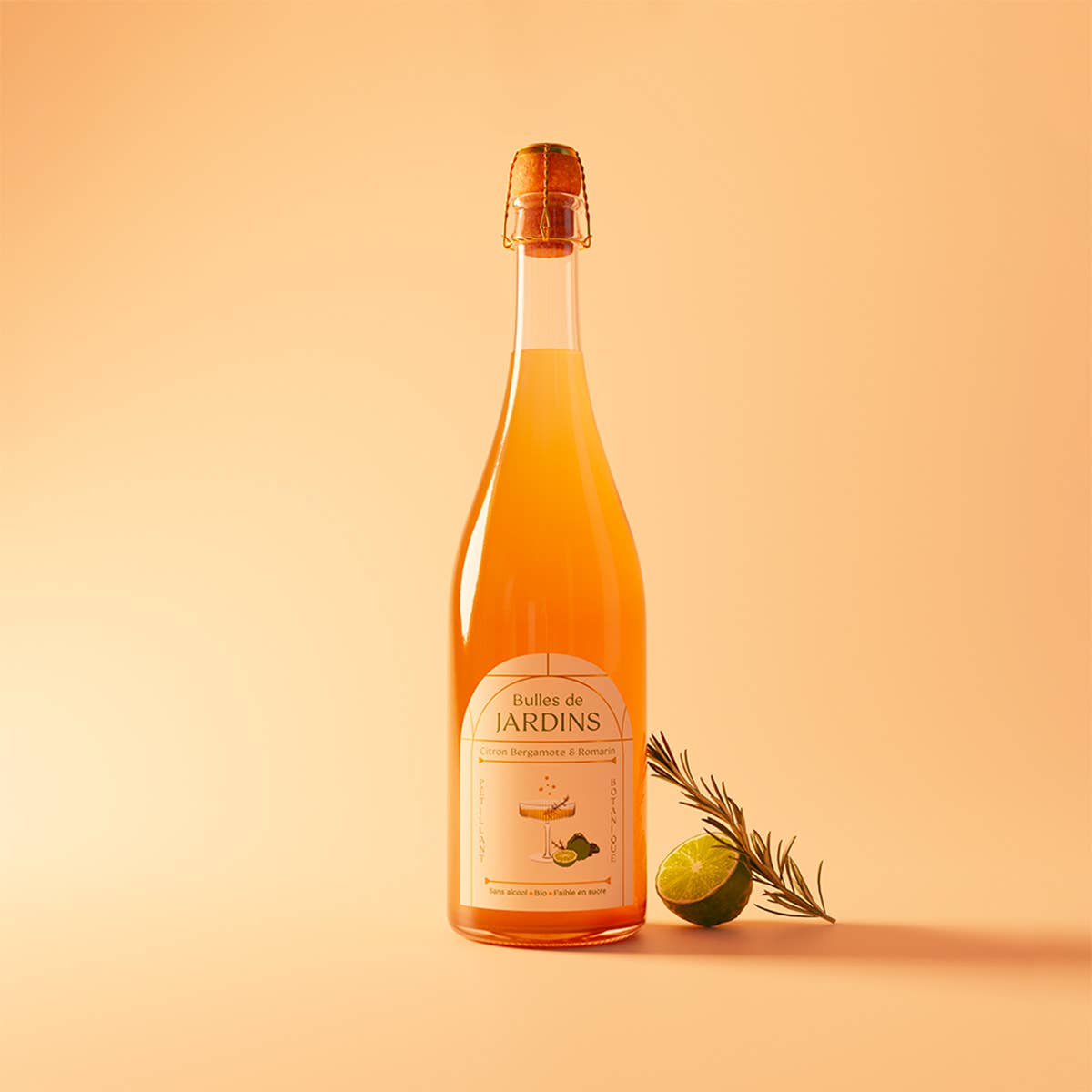 Bottle of Bubbles de Jardins Tonique alcohol-free sparkling wine, with rosemary and bergamot beside it, against a peach background.