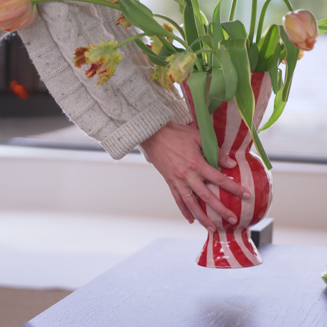 red and white vase being placed on table