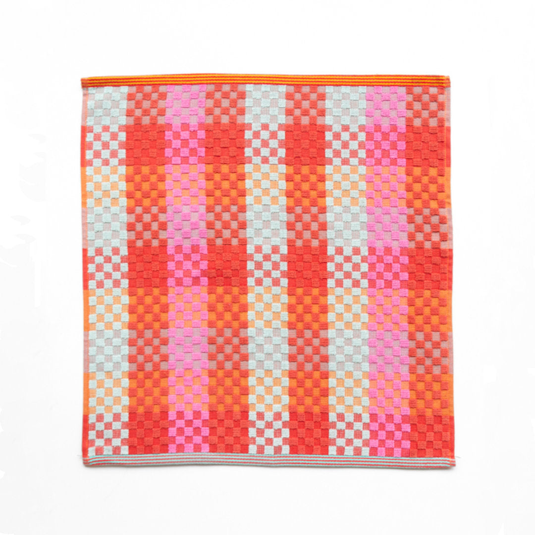 square kitchen cloth, brightly coloured with shades of red, pink, turquoise, orange and mint on a white background